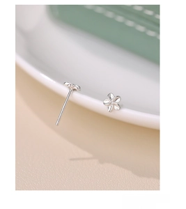 Macro detail of S999 sterling silver flower earrings showing fine texture and silver hallmark