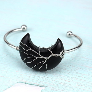 Macro detail of silver wire wrapped tree of life on black moon gemstone bracelet