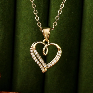 Macro detail of 18K gold plated heart necklace with sparkling zircon on green fabric