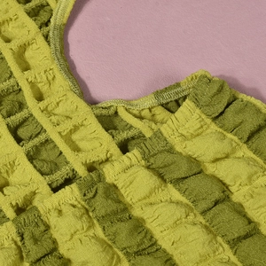 Detailopname van groene seersucker stof met getextureerde bubbelweving en fijne stiksels