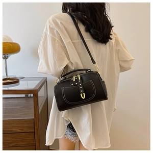 Détail d'un sac vintage en cuir noir avec surpiqûres blanches et rivets en métal doré