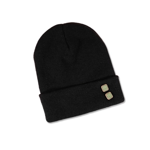 Detailed close-up of black knit beanie with olive green marble decorative buttons
