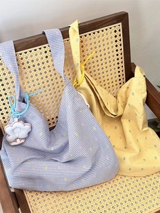 Pastel yellow and blue polka dot canvas tote bags displayed on a vintage rattan chair