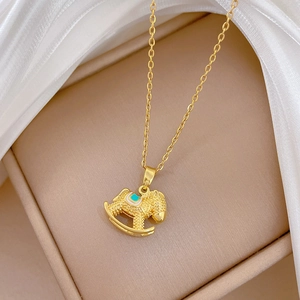 Macro shot of gold rocking horse pendant necklace with blue crystals on white silk fabric