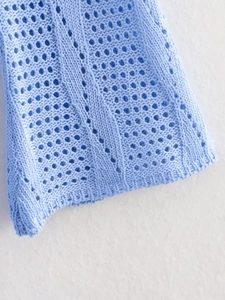 Détail macro du tissu tricoté bleu clair avec côtes verticales et découpes au crochet