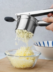 Action shot of stainless steel potato masher with black handle pressing cooked potatoes