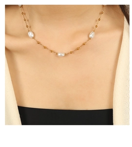 Close-up of model wearing gold 18k necklace with irregular white pearls and gold beads