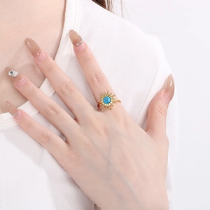 Gold sunflower ring with turquoise inlay on model hand with a white shirt background