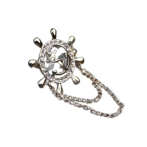 Broche nautique avec ancre et gouvernail, chaîne à pompon et strass sur fond blanc