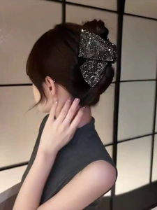 Detail of elegant black velvet bow hair claw clip with rhinestones worn by a model