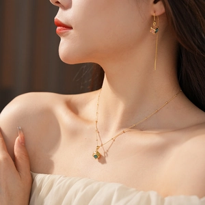 Close-up of gold-plated necklace and cube earrings worn by a model in warm light