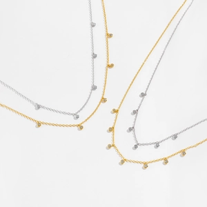 Macro detail of 925 silver and gold layered necklaces with round zircon charms