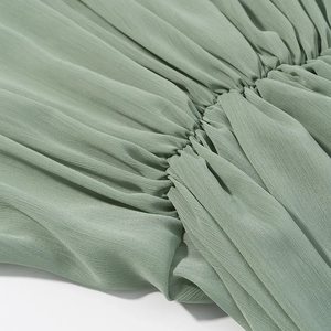 Detailed view of ruched pleats and high-density stitching on sage green V-neck dress