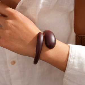 Detail of dark brown acrylic open bangle with smooth asymmetric water drop ends on wrist