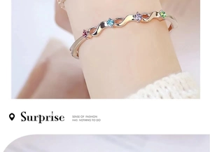 Close-up of gold wave bracelet with multi-color gemstones worn on a female wrist