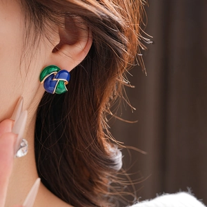 Detail of vintage blue and green enamel flower earrings worn on a model's ear
