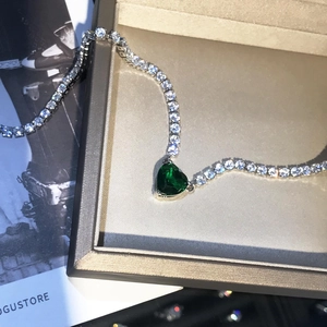 Sparkling heart-shaped green emerald necklace with diamond-set chain on display