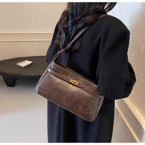 Borsa a tracolla vintage marrone scuro con chiusura dorata indossata sulla spalla