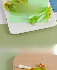 Realistic artificial scallion miniature used as decorative photography prop on a wooden board