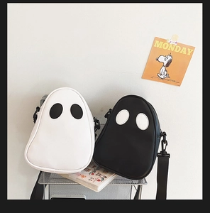 Black and white cartoon ghost crossbody bags on a metal display shelf with shoulder straps
