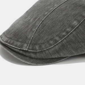 Close-up of vintage washed denim flat cap showing high-quality stitching and dark grey texture