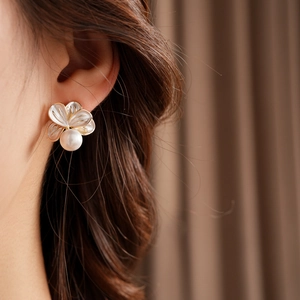Détail d'une boucle d'oreille fleurie avec perle sur mannequin aux reflets nacrés vintage