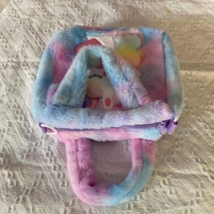 Close-up of plush tie-dye unicorn handbag with soft pink, blue, and purple faux fur textures