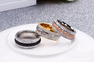 Detailed view of three-color crystal studded rotating rings in gold, rose gold and black