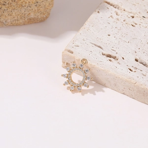 Detailed view of a gold sun pendant with white cubic zirconia on natural beige stones