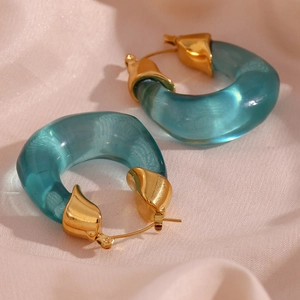 Detailed close-up of chunky green acrylic U-shaped earrings with gold metal accents