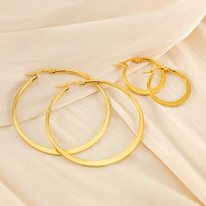 Polished 18K gold-plated stainless steel hoop earrings set on soft beige silk fabric
