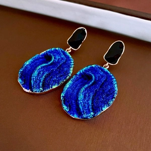 Macro shot of vintage style earrings with dark blue stone and gold plated metal frame