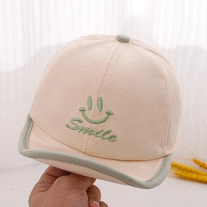 Détail de la casquette bébé avec broderie sourire verte et texture coton doux