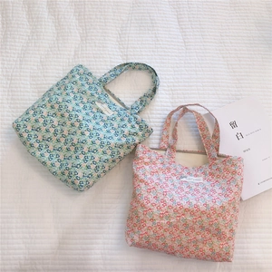 Gros plan de sacs cabas en coton fleuri aux motifs bleu-vert et rose-orange sur fond blanc