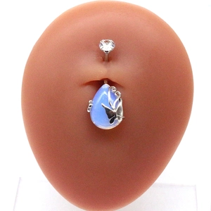 Detailed close-up of a silver belly ring with a blue teardrop stone on a model navel