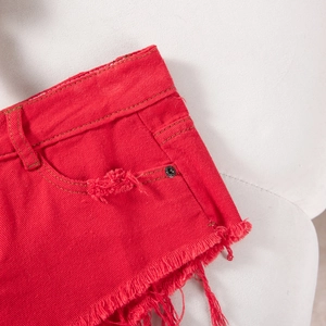 Nahaufnahme roter Jeans-Shorts mit ausgefranstem Saum und Nieten an den Taschen