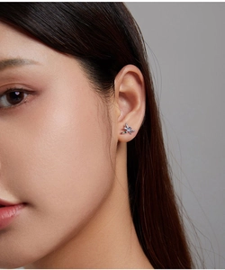Detail of colorful dragonfly stud earrings with micro-inlaid gems on a model's ear