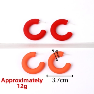 Detail view of red and orange C-shaped acrylic earrings with 3.7cm diameter and 9mm width