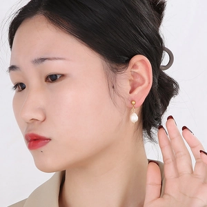 Gros plan d'un mannequin portant une boucle d'oreille en perle plaquée or 18 carats