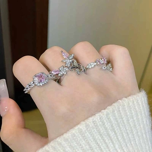 Detail of silver rings featuring pink zircons, butterfly designs and floral elements