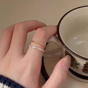 Detail of 925 sterling silver anchor chain rings worn on fingers with a lifestyle backdrop