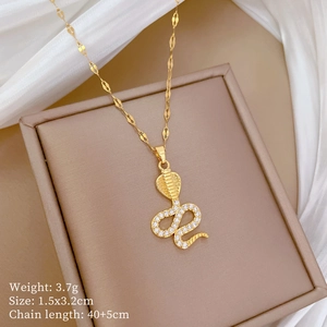Macro shot of gold cobra pendant with white zircons on white silk background