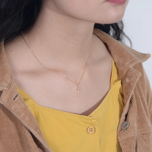 Detail of a minimalist gold cross pendant necklace with diamonds on a female model
