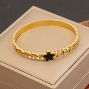 Détail d'un bracelet jonc plaqué or 18K avec fleur noire et structure de vigne évidée