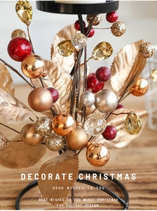 Macro view of gold leaves and red baubles on a black iron Christmas candle holder