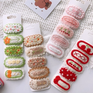 Close-up of handmade knitted floral hair clips in assorted pastel colors on card