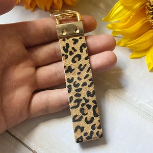 Close-up of leopard print leather keychain with gold metal clasp and animal hair texture