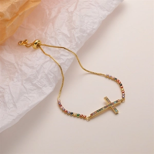 Detail of adjustable gold box chain bracelet with colorful zircon heart and cross pendant