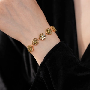 Detailed close-up of vintage flower bracelet with olive green zircons on a golden chain