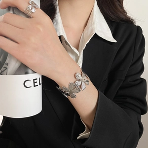 Macro detail of silver floral bracelet and matching ring set with hollow petals